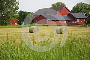 Old red barn with round bales of hay in the foreground