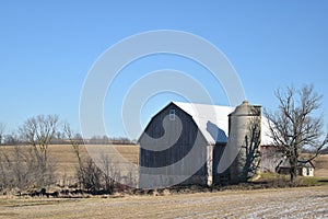 Old red barn with silo on a farm in late autumn on a sunny day