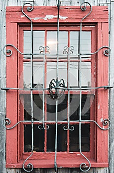 Old red barn window full frame with ornate wrought iron cover, historic