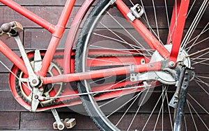Old red bike on the background of a brown wooden wall