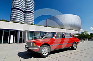 Old red BMW series 3 coupe standing next to BMW Museum in Munich, Germany