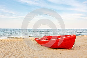 Old red boat on the beach, waves on the water and clouds background