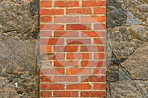 Old red brick on the background of a wall of natural stone