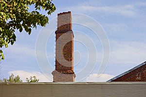 Old red brick chimney against blue sky