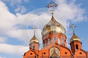 Old red brick Christian church with gold and gilded domes against a blue sky. Concept faith in god, orthodoxy, prayer