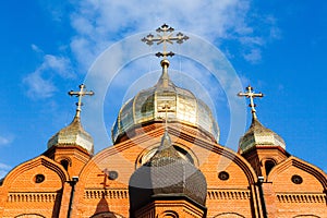 Old red brick Christian church with gold and gilded domes against a blue sky. Concept faith in god, orthodoxy, prayer