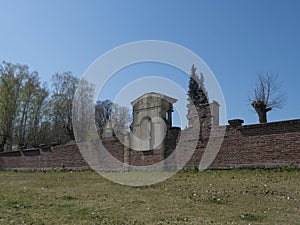 Old red brick wall of country cemetery at village Cvikov in luzicke hory, Lusatian Mountains, early spring, blue sky