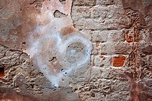 Old red brick wall with cracks and scratches and painted heart. Distressed wall with broken bricks texture