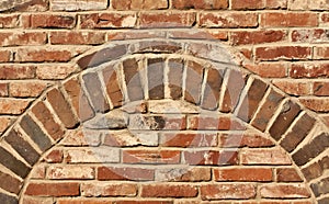 Old red brick wall texture with arch.