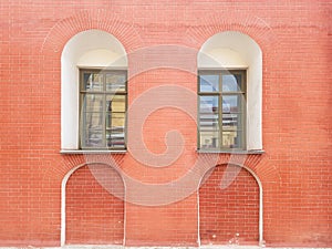 An old red brick wall and two green windows on it