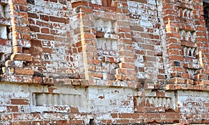 An old red brick wall with white fallen plaster.