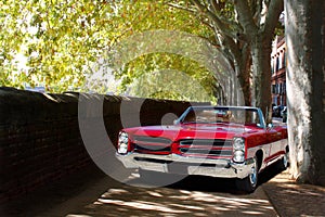 Old red Cadillac Coupe in an avenue