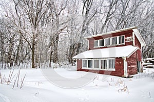 Old red chicken coop covered in snow.