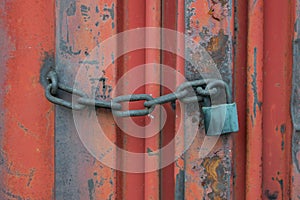 Old red container door with a lock on a chain