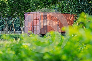 Old red container in the middle of the green park.