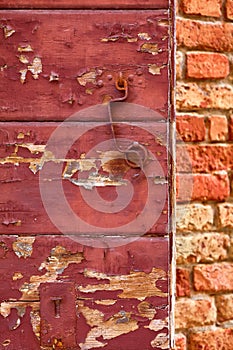 Old red cracky wooden door with flacky paint rusty metal handle