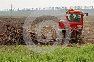 An old red crawler tractor works in the field