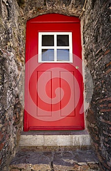 Old red door on a stone building.