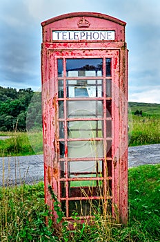 Old red English phone booth in countryside