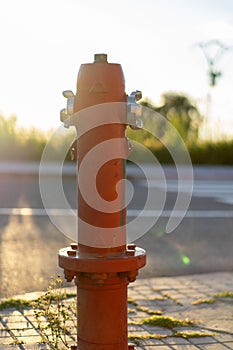 Old red fire hydrant at sunset.