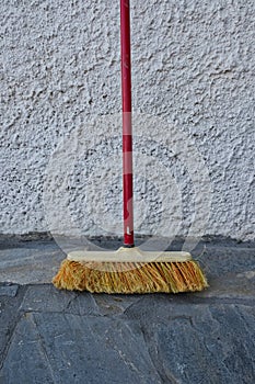 An Old Red Handled Broom Leaning on Wall