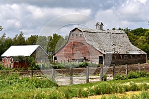 An old red hip roofed barn in serious deterioration