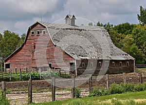 An old red hip roofed barn in serious deterioration