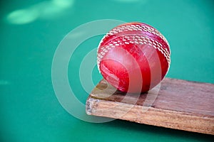 An old red leather cricket ball on bat