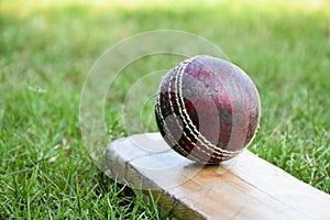 An old red leather cricket ball on bat