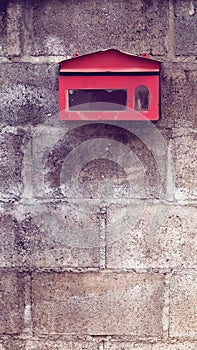 Old red mailbox on concrete wall.