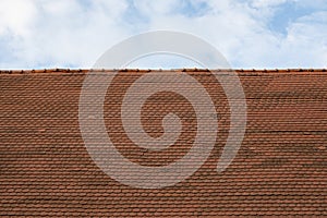 Old red metal tile roof against sky