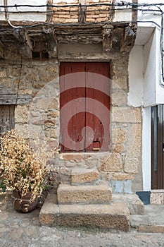 An old red painted wooden door with a cat flap
