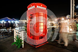 Old red payphone surrounded with people