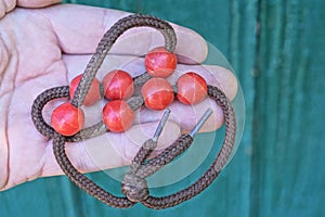 old red round plastic beads on a brown lace lie on a hand