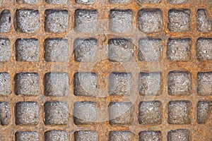 Old red rusty metal sewer manhole with checkered pattern. rough surface texture