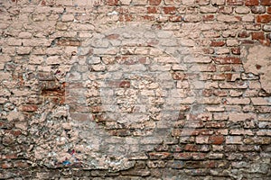 Old red shabby damaged brick wall with gray cement, stains of white paint. rough surface texture