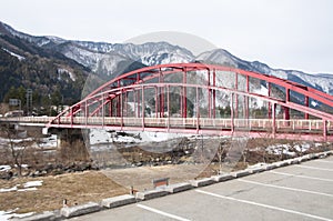 Old red steel bridge crossing the river in Japan.