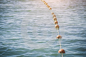 Old red styrofoam buoys on the rope lying on the beach of the sea