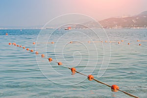 Old red styrofoam buoys on the rope lying on the beach of the sea