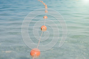 Old red styrofoam buoys on the rope lying on the beach of the sea