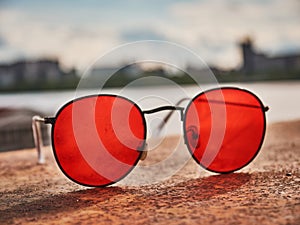 Old red sunglasses on a concrete surface. Scratched glass