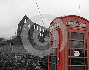 Old red telephone box in front of a derelict slate mill