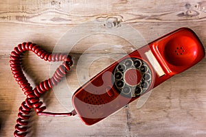 Old red phone forming a heart with the cable photo