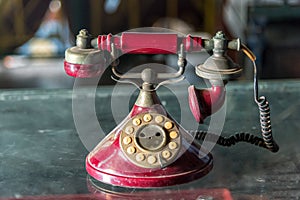 Old red telephone with rotary dial on glass table