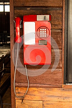 Old red telephone on a wooden wall.