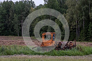 An old red tracked tractor stands abandoned