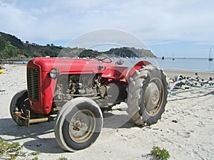 Old red tractor on a beach