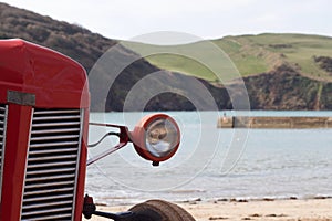 Old red tractor front on Hope Cove beach, Devon, England