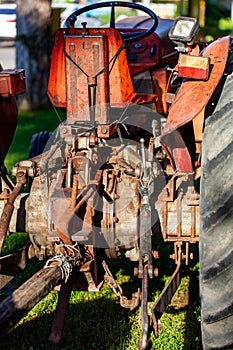 An old red tractor near a farm field.