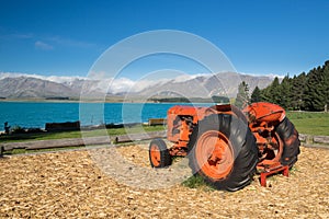 An old red tractor on the shore of lake Tekapo, New Zealand